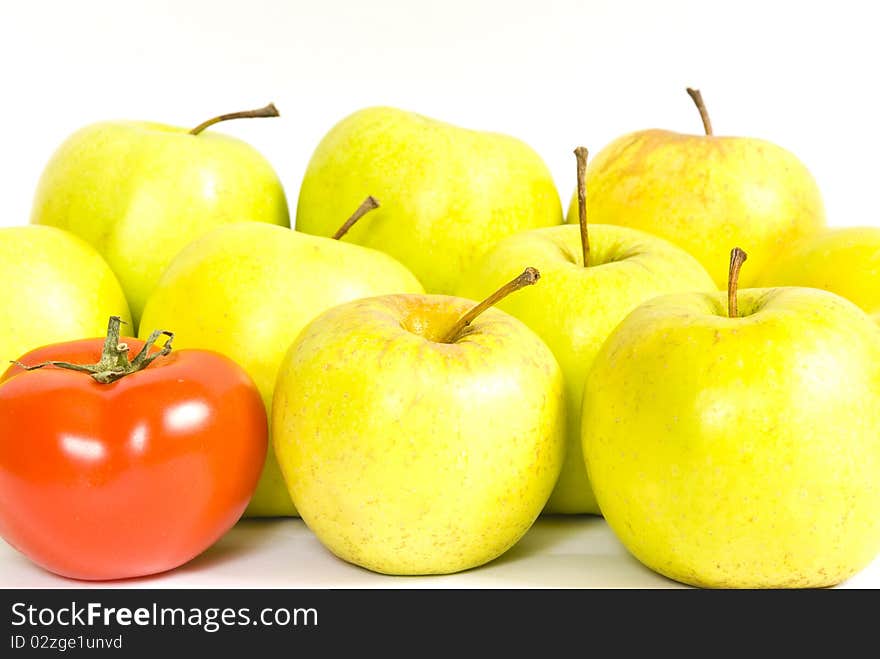 A red tomato and a few green apples lying group, on a white background. A red tomato and a few green apples lying group, on a white background