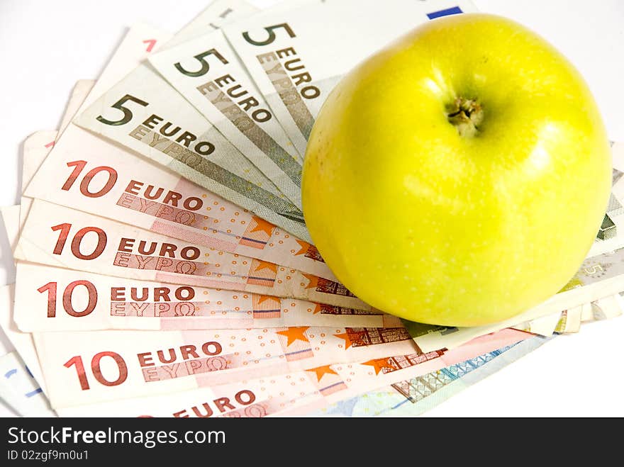 Green apple lying on the banknotes of different denomination, lying like a fan. on a white background. Green apple lying on the banknotes of different denomination, lying like a fan. on a white background