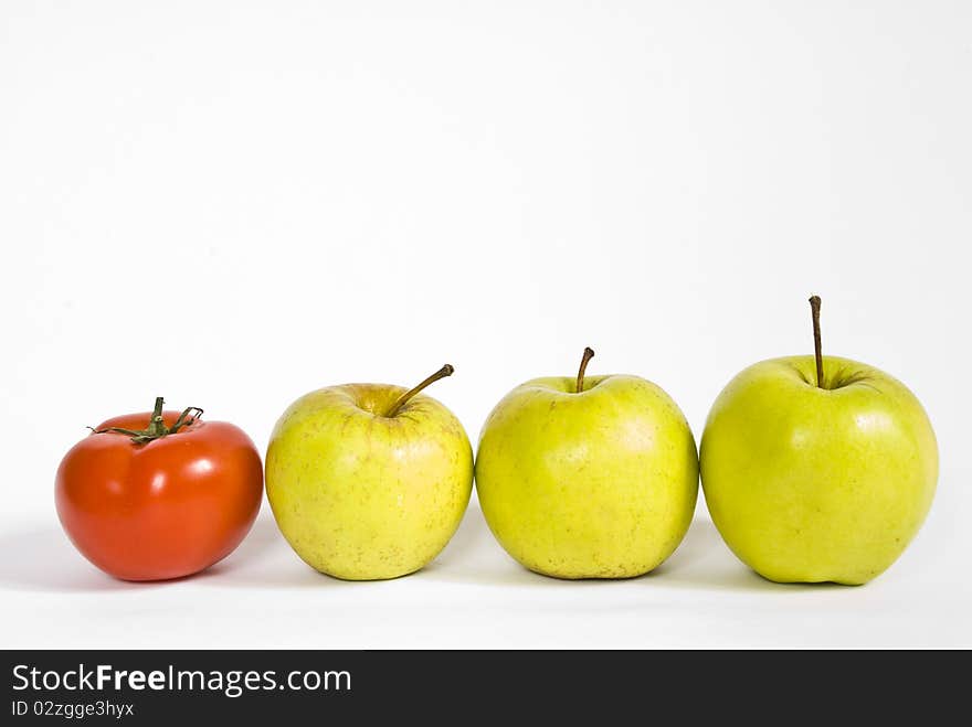 Red ripe tomato, and green apples lying in a row on a white background. Red ripe tomato, and green apples lying in a row on a white background