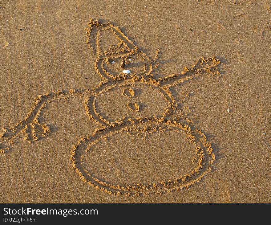 Draw of snowman on yellow sand of the beach.