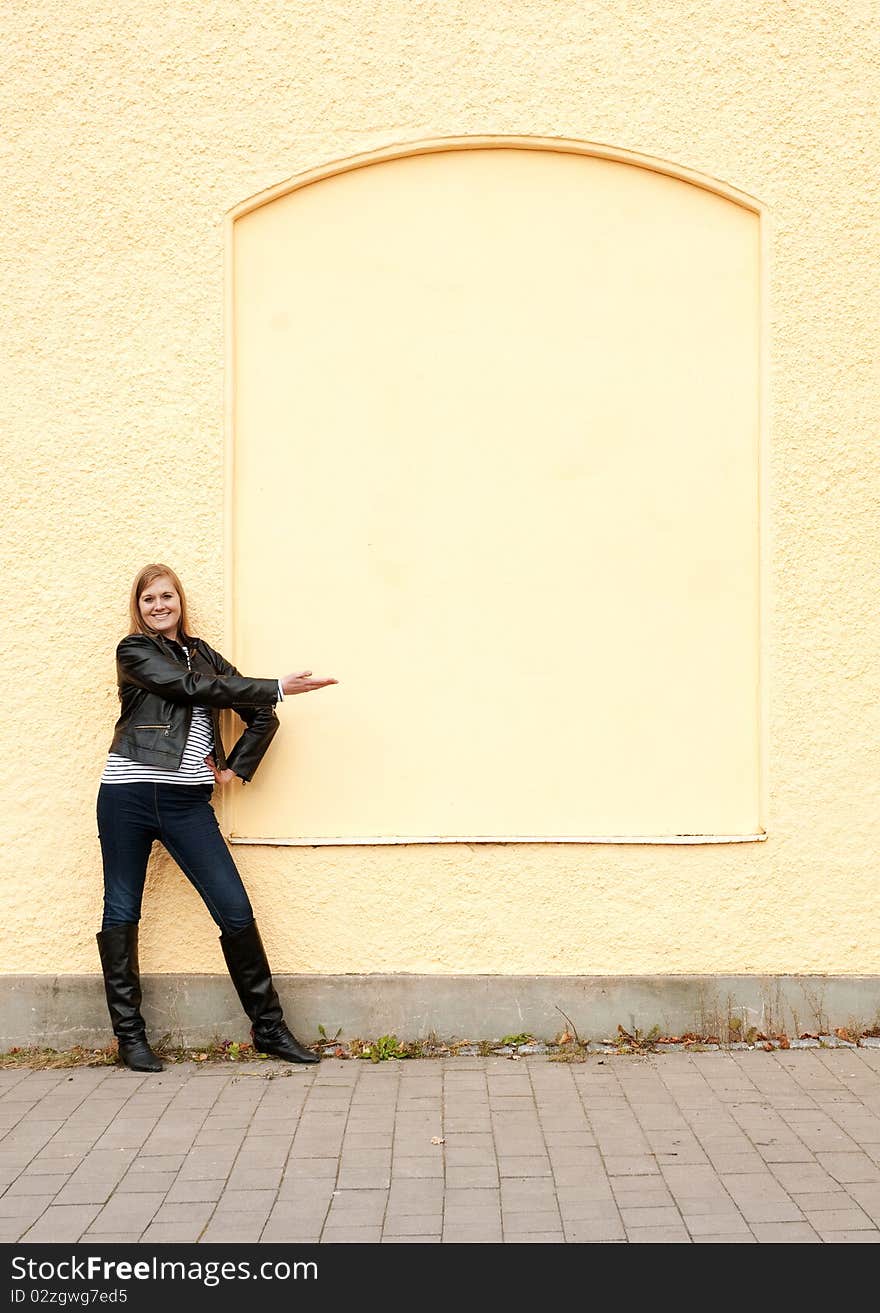 Girl standing in front of wall pointing. Girl standing in front of wall pointing.