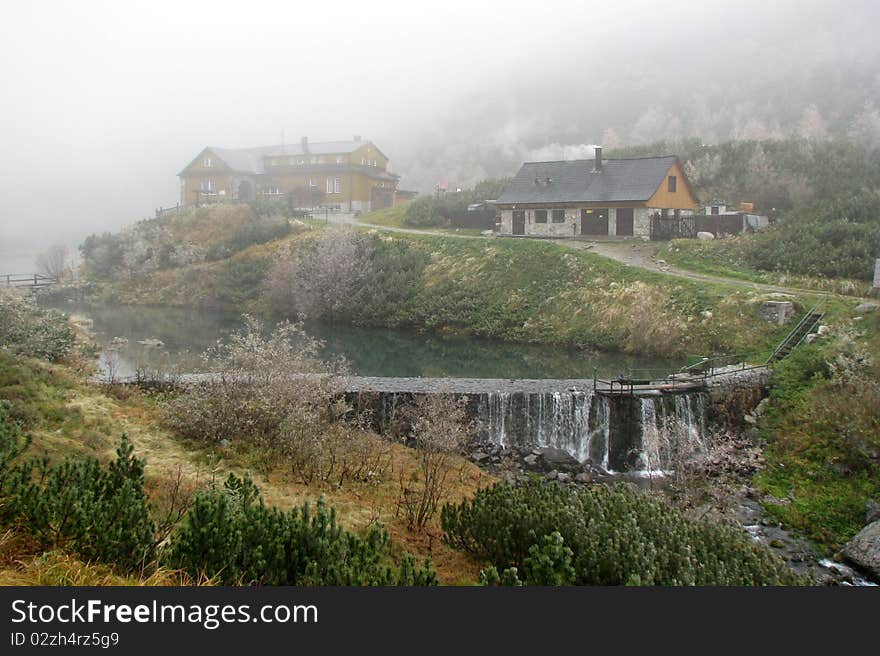 Foggy day in forest during autumn high in mountains. Cottage and waterfall. Foggy day in forest during autumn high in mountains. Cottage and waterfall.