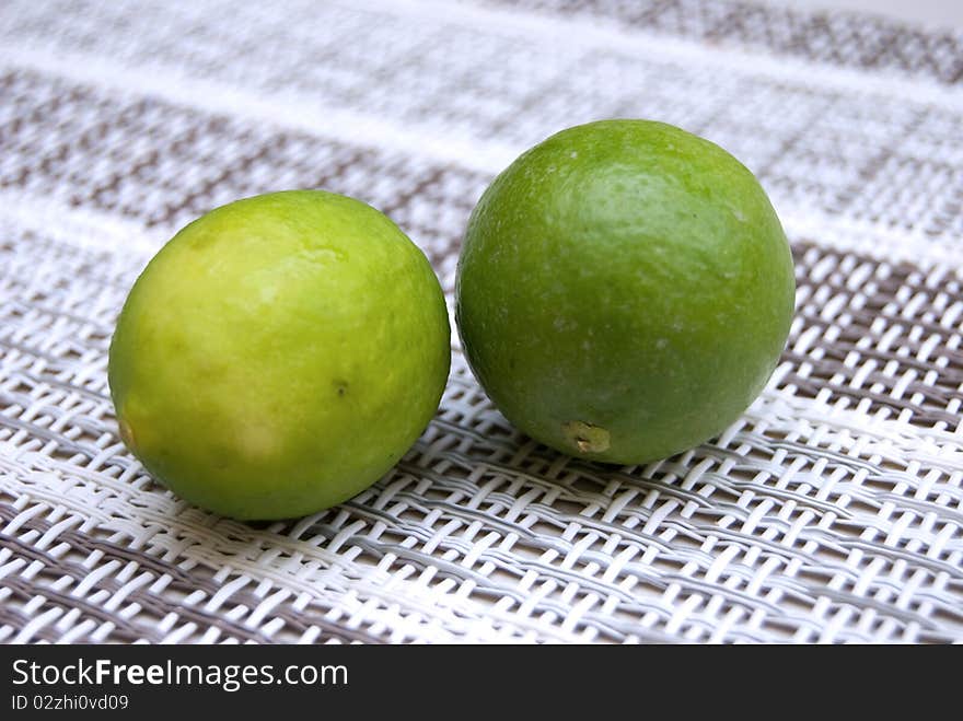 Two small limes, one yellow and one green. Two small limes, one yellow and one green