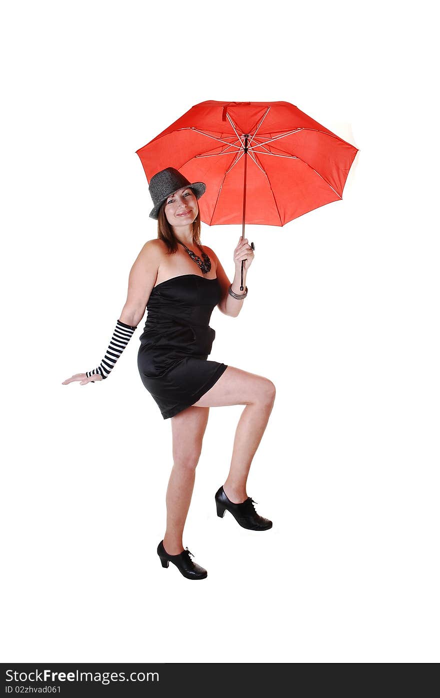 An middle aged woman in an short black dress and a gray hat standing in the studio with a red umbrella in her hand. An middle aged woman in an short black dress and a gray hat standing in the studio with a red umbrella in her hand.