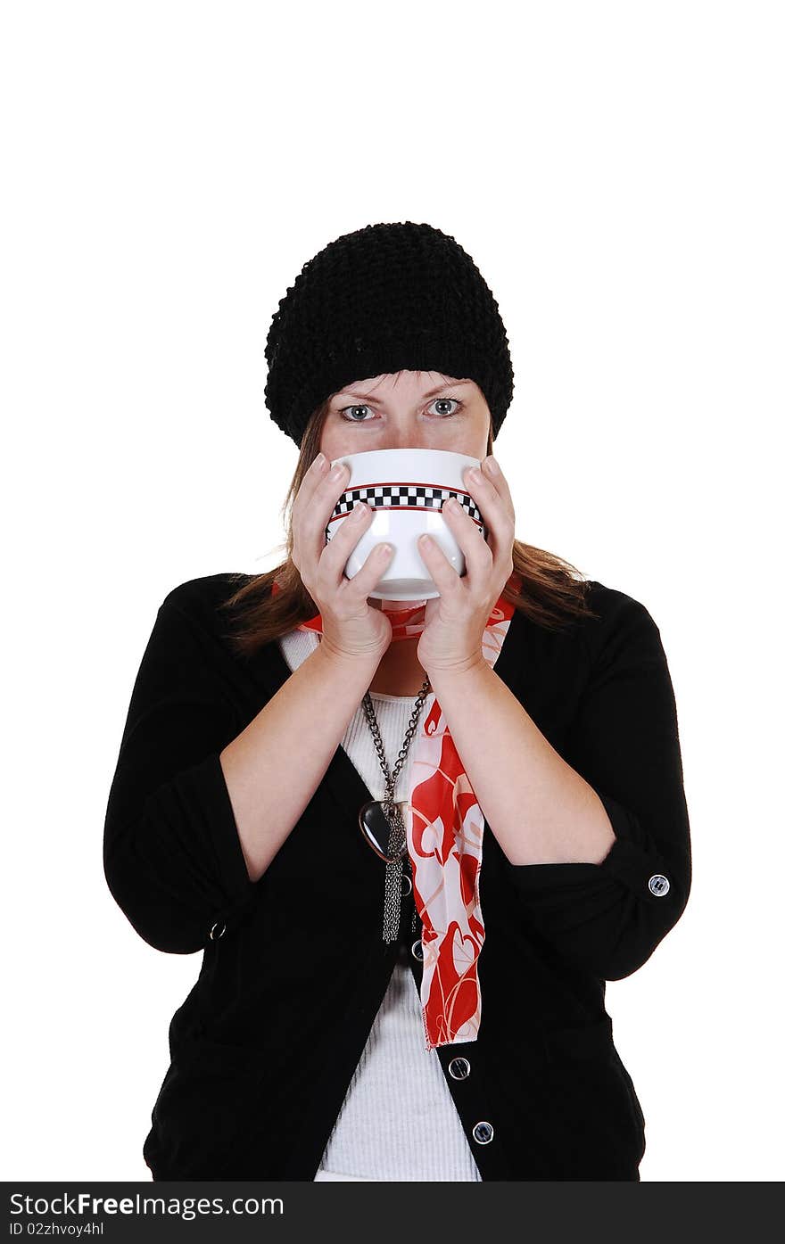 A middle aged woman drinking from a big cup some hot tea, with a sweater,scarf and hat on. A middle aged woman drinking from a big cup some hot tea, with a sweater,scarf and hat on.