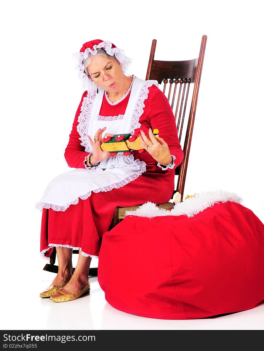 Mrs. Claus inspecting one of Santa's toys before loading it into his sack.  Isolated on white. Mrs. Claus inspecting one of Santa's toys before loading it into his sack.  Isolated on white.