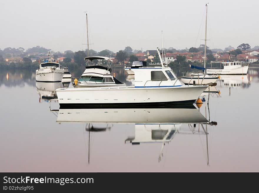 Boats moored on calm glassy water.