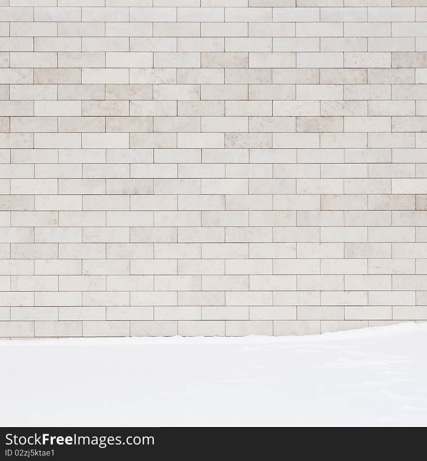 A white brick wall and a ground covered with snow. May use as a background.