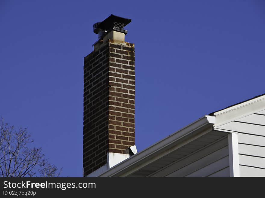 A red brick chimney against a blue sky.