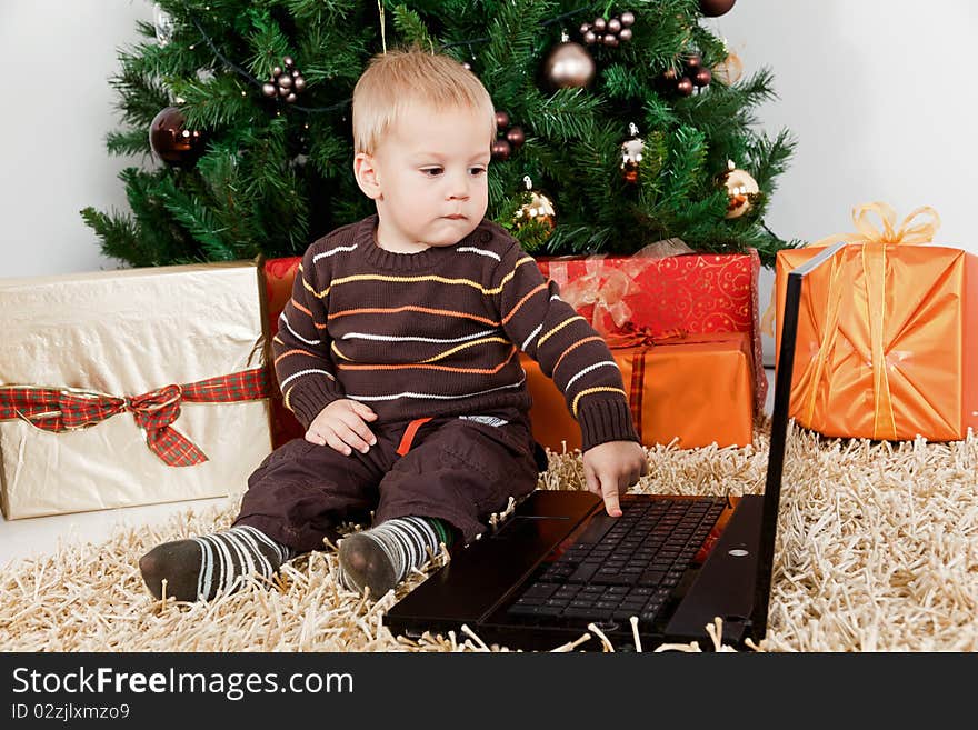 Sweet baby boy playing with a laptop at christmas