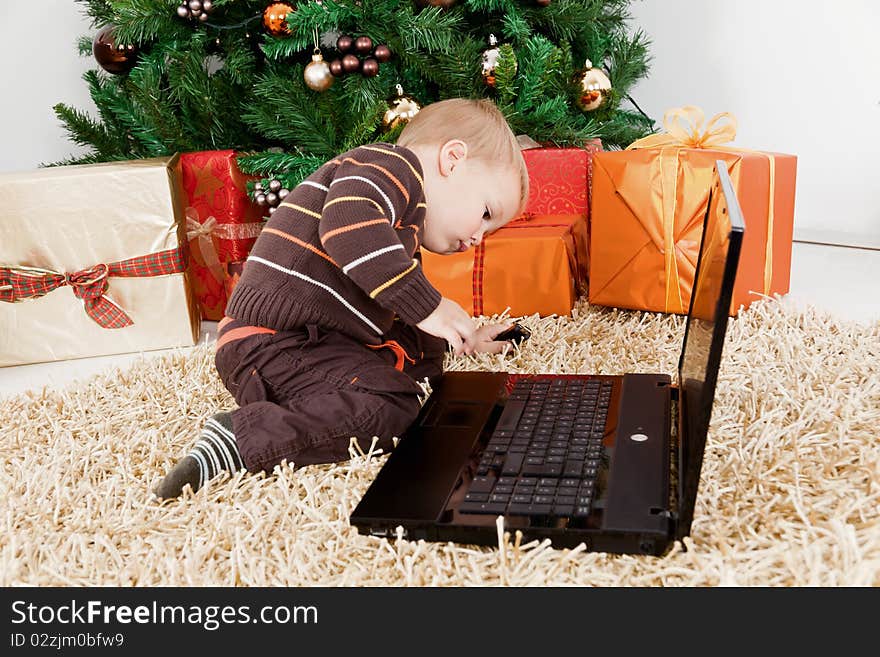 Sweet baby boy playing with a laptop at christmas