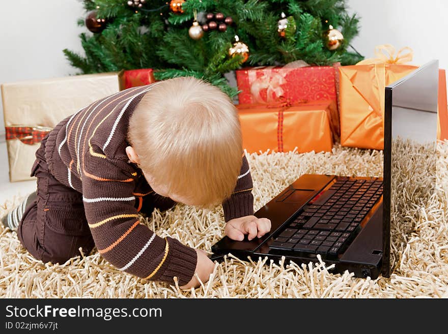 Baby boy playing with a laptop at christmas