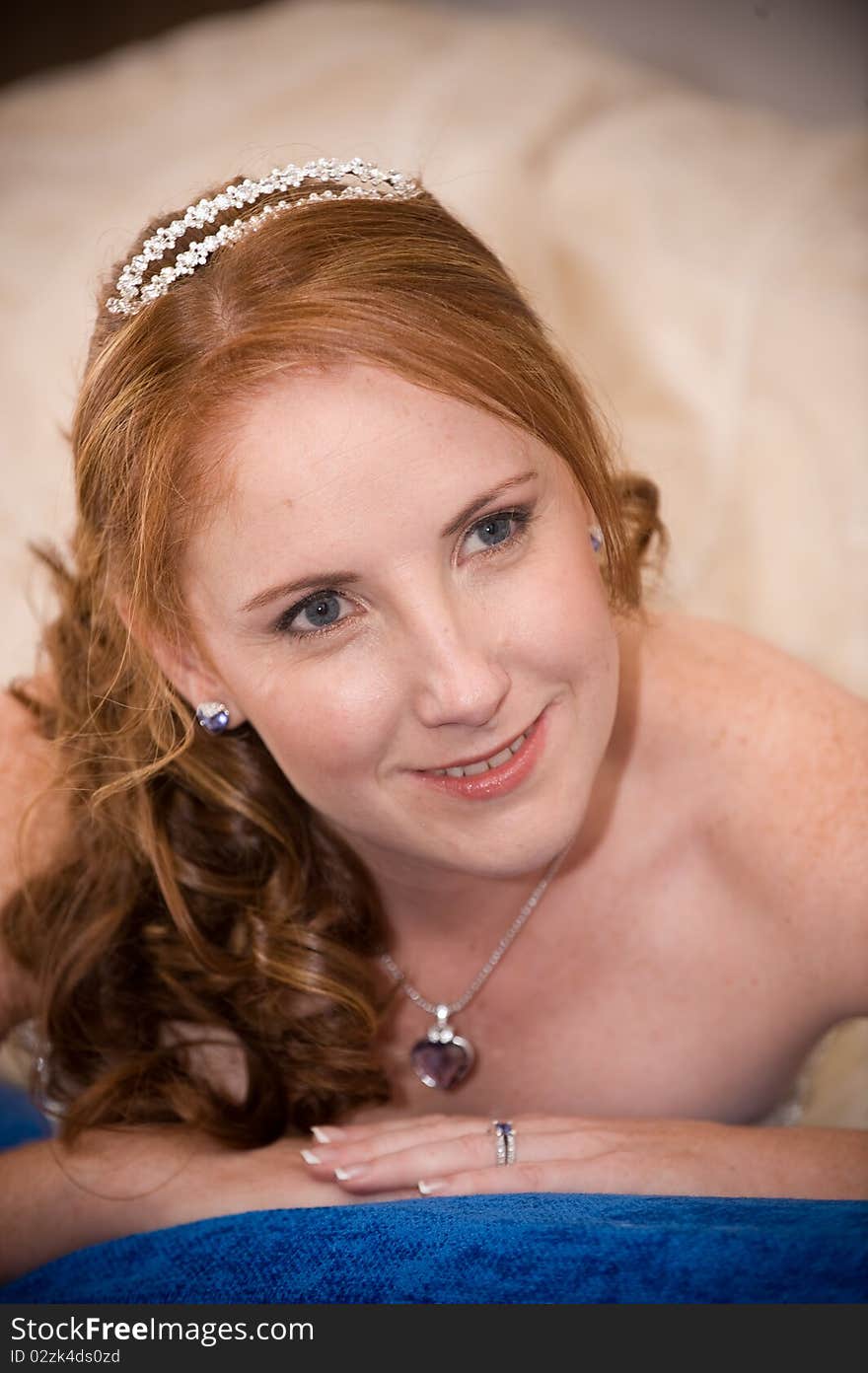 Red head beautiful bride laying down on her elbows with cleavage visible and leaning on her hands whilst smiling. Red head beautiful bride laying down on her elbows with cleavage visible and leaning on her hands whilst smiling