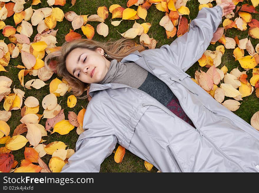 Beautiful girl rests upon autumn sheet and green herb