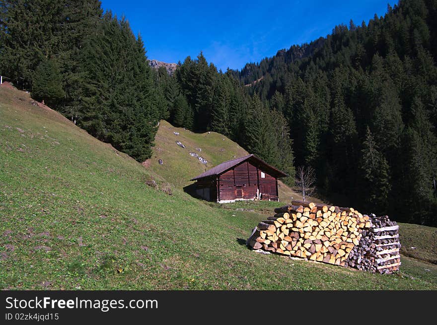 Swiss mountain scene: wooden hut and woodpile in forest mountains. Swiss mountain scene: wooden hut and woodpile in forest mountains