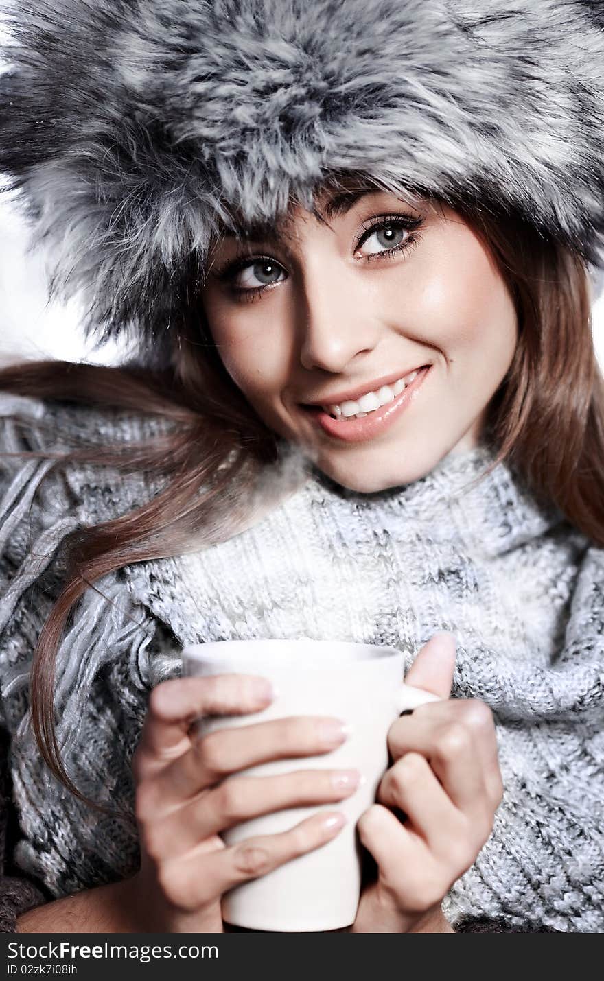 Girl blowing on hot drink dressed in winter clothing