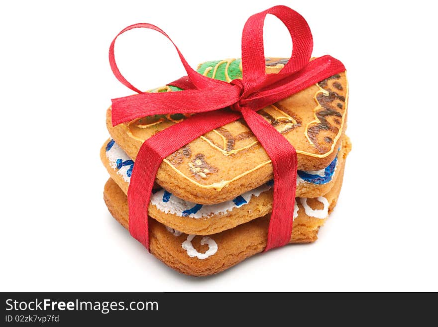 A stack of Christmas cookies in the amount of three pieces. Cookies in the shape of little houses. Pile tied a red ribbon. Painted and baked cookies manually. Isolated on white background. A stack of Christmas cookies in the amount of three pieces. Cookies in the shape of little houses. Pile tied a red ribbon. Painted and baked cookies manually. Isolated on white background.