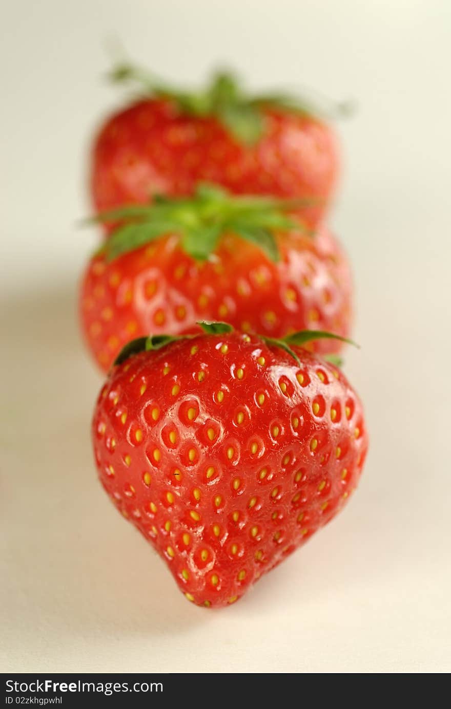 3 Fresh Ripe Red Strawberries in a line with the first in sharp focus and the others out of focus. 3 Fresh Ripe Red Strawberries in a line with the first in sharp focus and the others out of focus