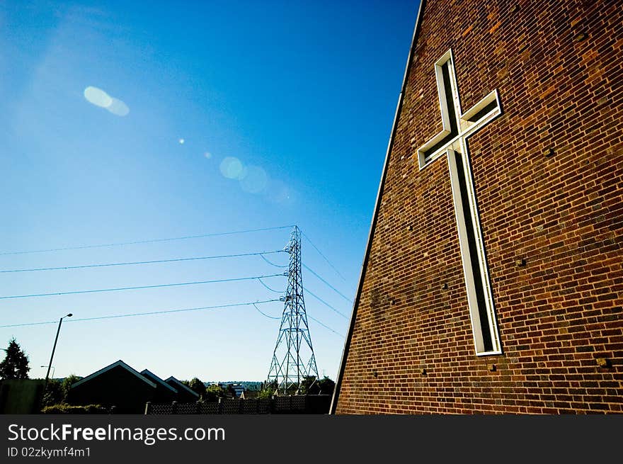 A cross on the side of an unually shaped church. A cross on the side of an unually shaped church.