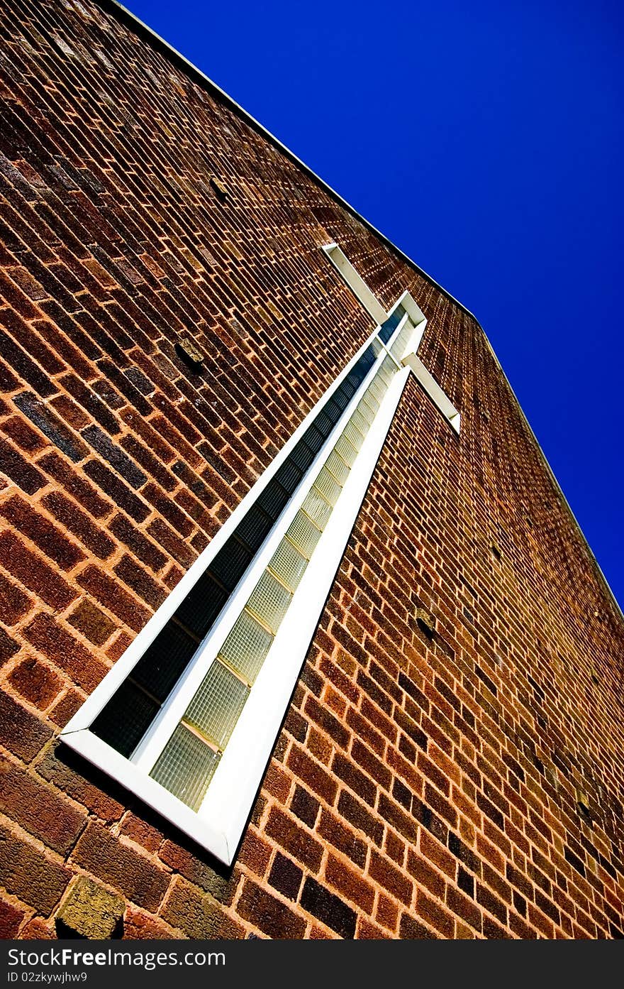 A cross on the side of an unually shaped church. Taken close up with a wide angle lens. A cross on the side of an unually shaped church. Taken close up with a wide angle lens.