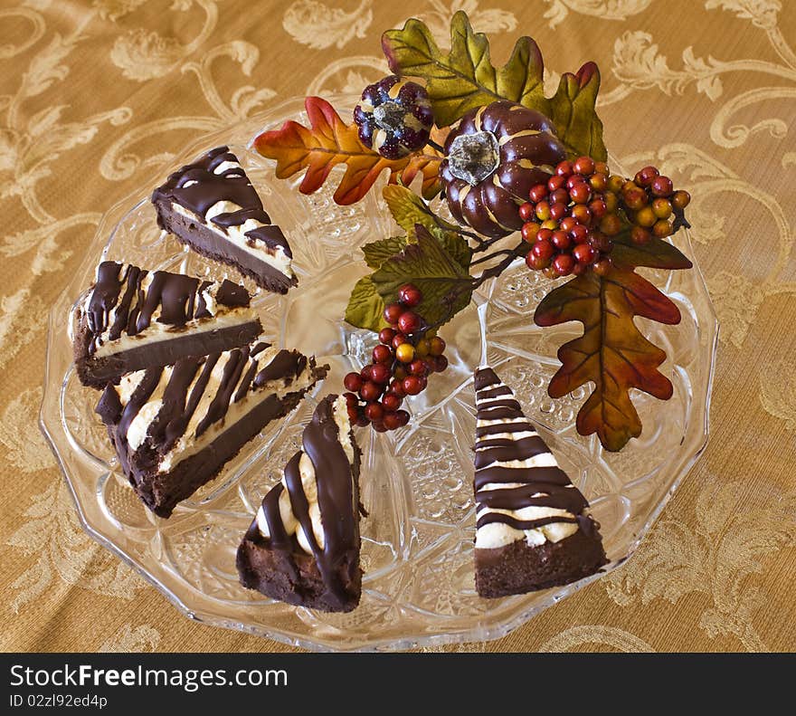 Cheesecake slices on a glass plate on a gold brocade table cloth with autumn greenery decorations