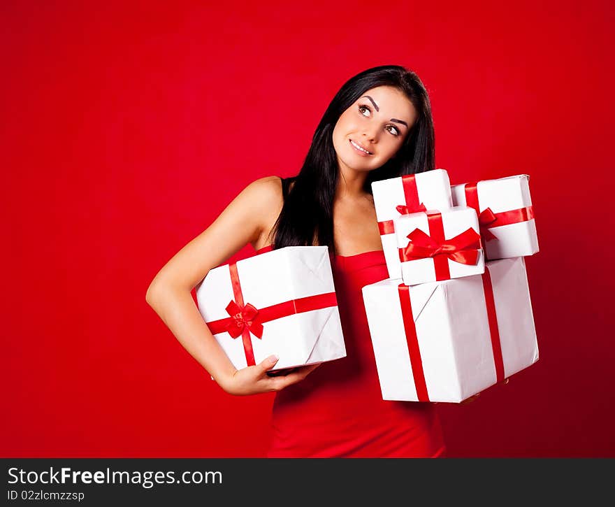 Pretty young brunette woman dressed in red dress with many presents. Pretty young brunette woman dressed in red dress with many presents