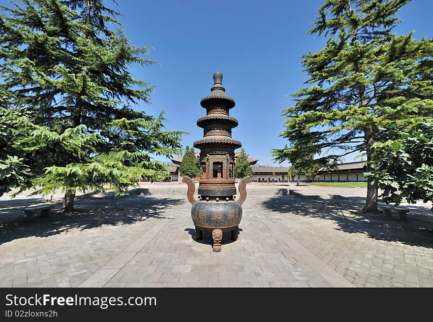 An old censer in Chinese temple courtyard in wide view angle, surround with traditional architecture and trees in radial and symmetrical. An old censer in Chinese temple courtyard in wide view angle, surround with traditional architecture and trees in radial and symmetrical.