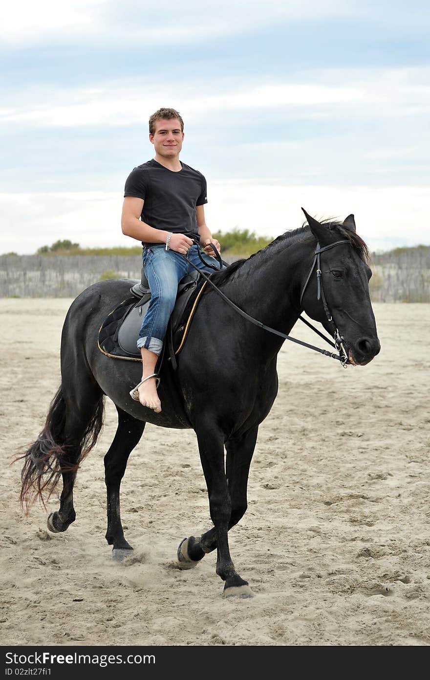 Young man and his black stallion on the beach. Young man and his black stallion on the beach