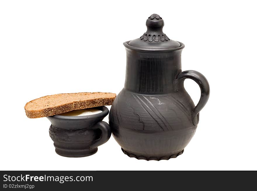 Milk in the cup, pitcher made of black clay and rye bread with caraway on a white background. Milk in the cup, pitcher made of black clay and rye bread with caraway on a white background