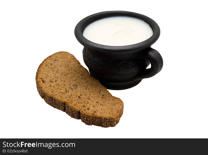 Milk in the cup made of black clay and rye bread with caraway on a white background. Milk in the cup made of black clay and rye bread with caraway on a white background