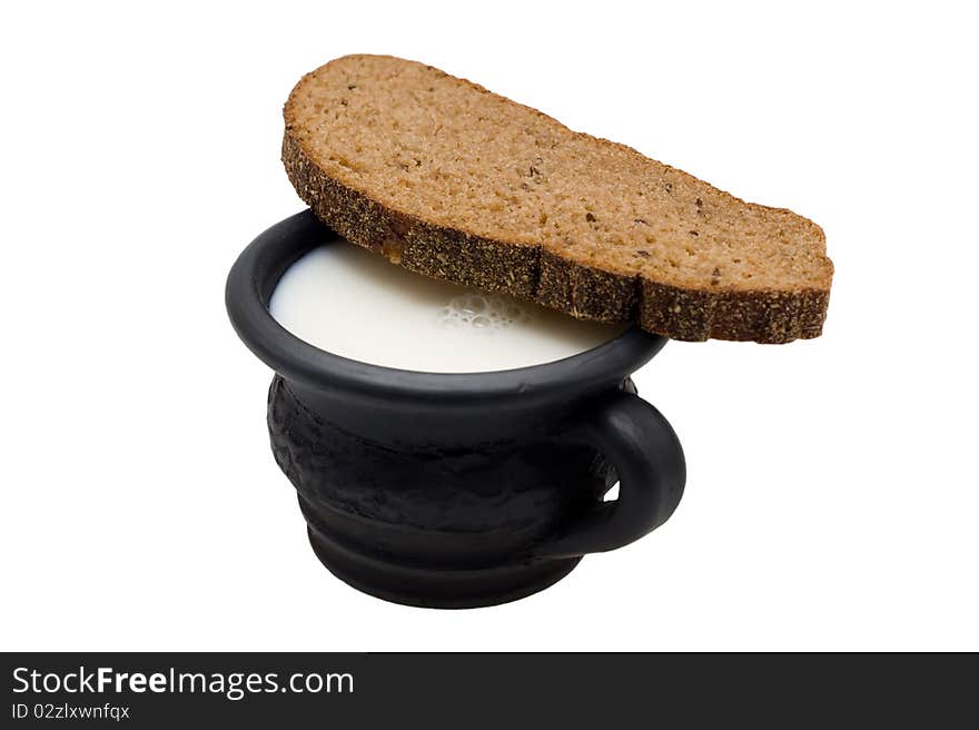 Milk in the cup made of black clay and rye bread with caraway on a white background. Milk in the cup made of black clay and rye bread with caraway on a white background