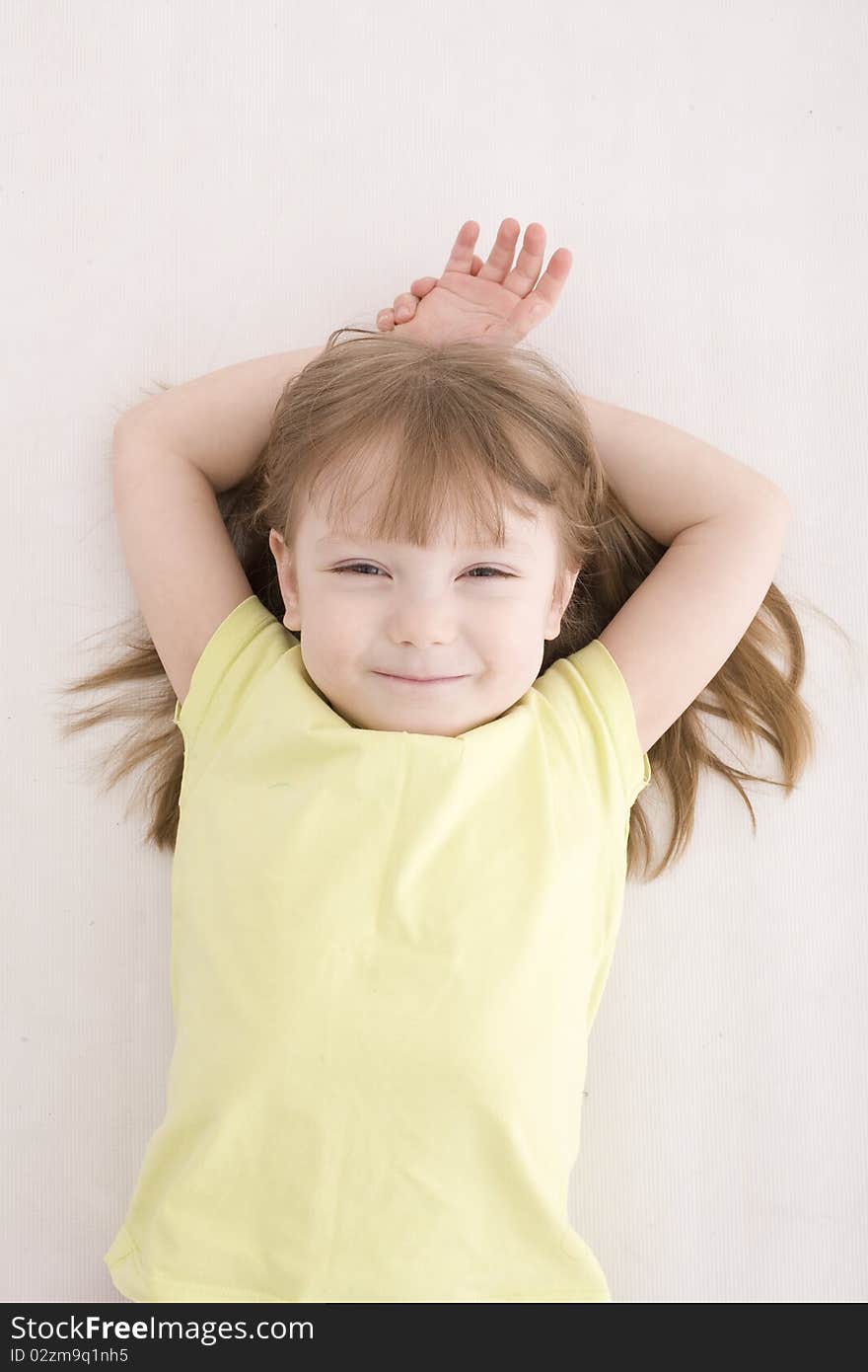 The portrait of a cute little girl standing on the floor and looking at the camera