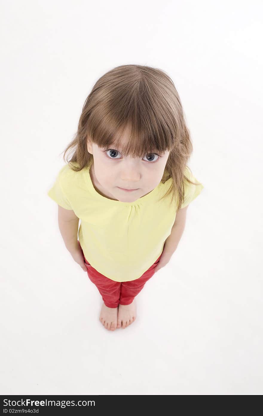 The portrait of a cute little girl standing on the floor and looking at the camera