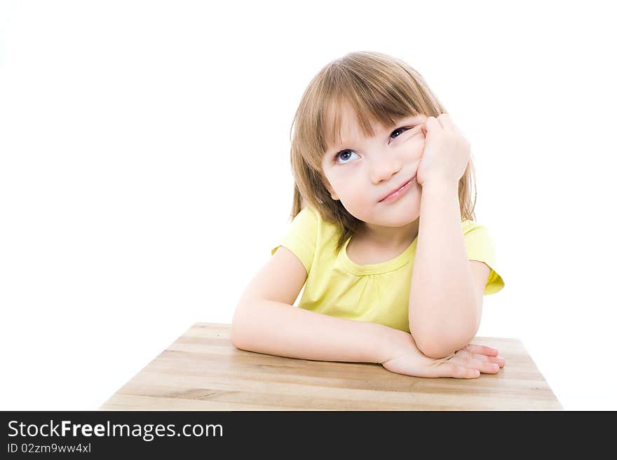 The portrait of a clever little girl sitting at the table