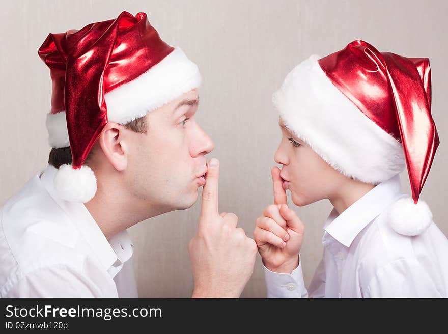 Father and son in santa hat showing silence sign. Father and son in santa hat showing silence sign.