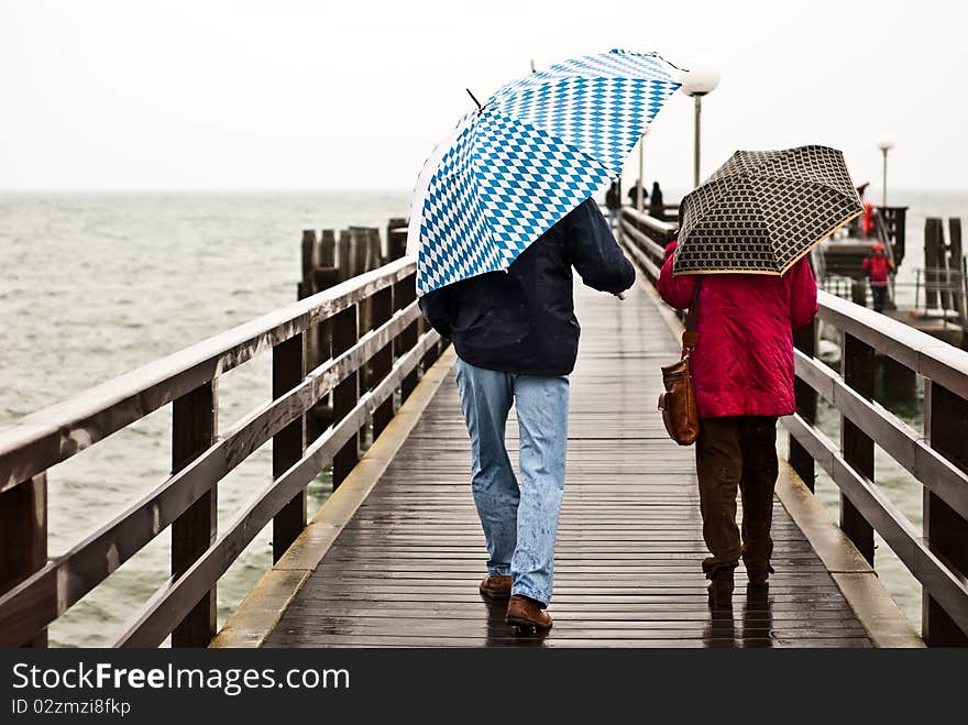 Two people with an umbrella on the pier. Two people with an umbrella on the pier