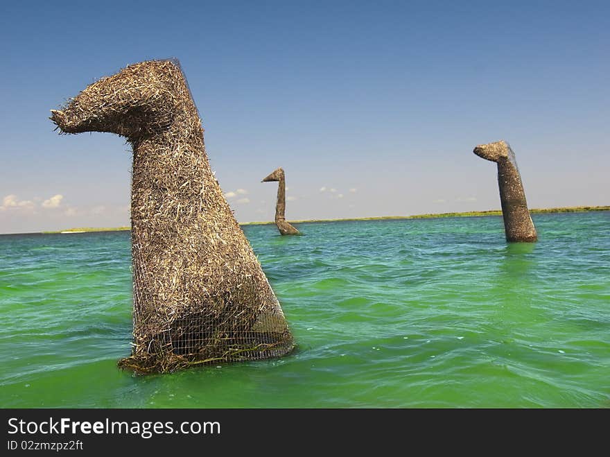 Three straw dinosaurs wade through shallow waters on this island.