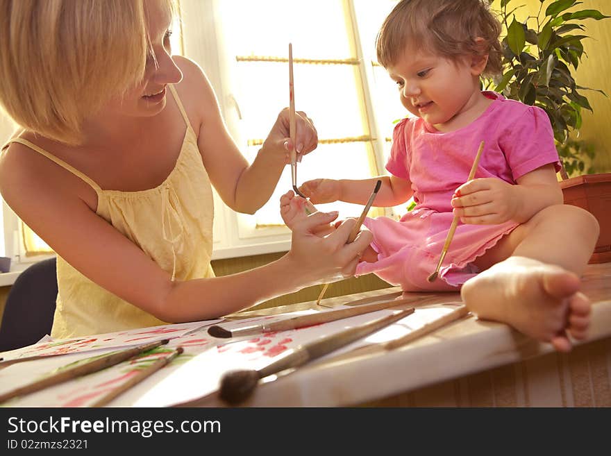 Mother drawing a flower on her daughter heel. Mother drawing a flower on her daughter heel