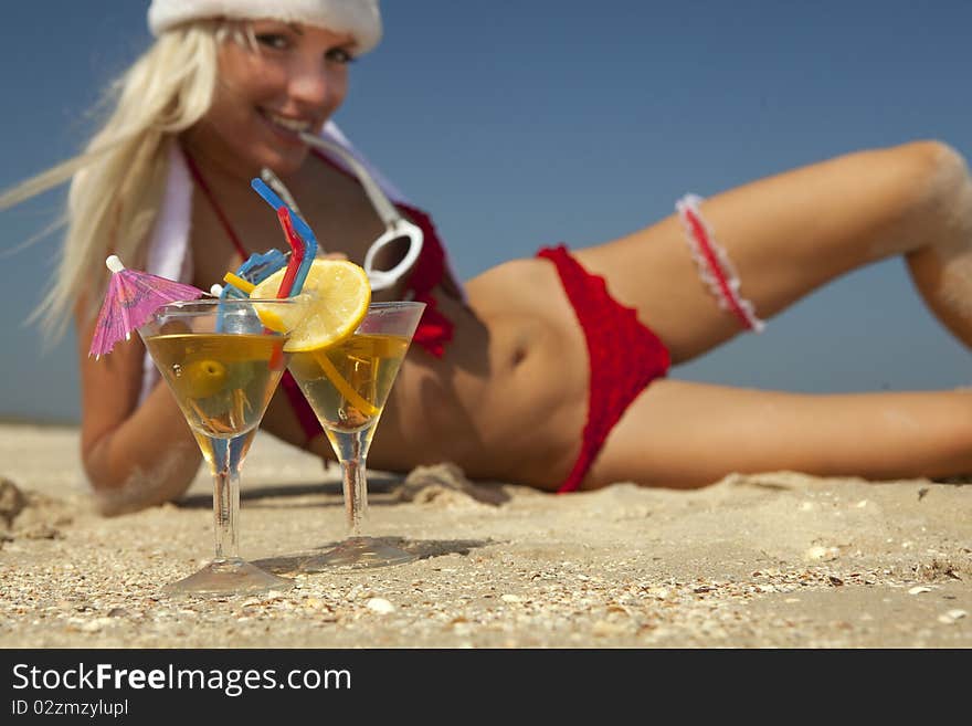 Young women in christmas suit with two martini glasses on the beachfront (Focus on martini glasses). Young women in christmas suit with two martini glasses on the beachfront (Focus on martini glasses)