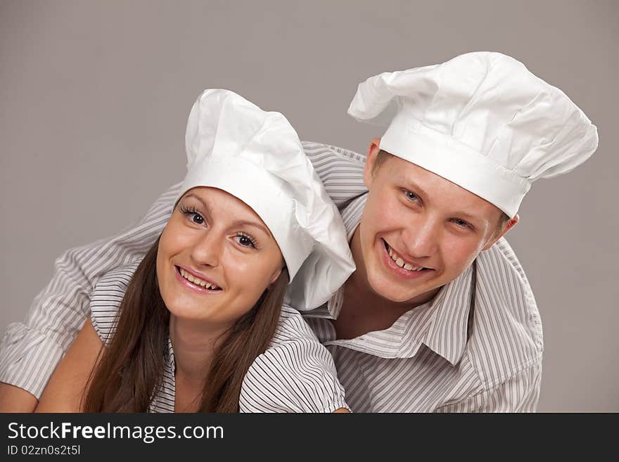 Young loving couple cooks. Over gray background