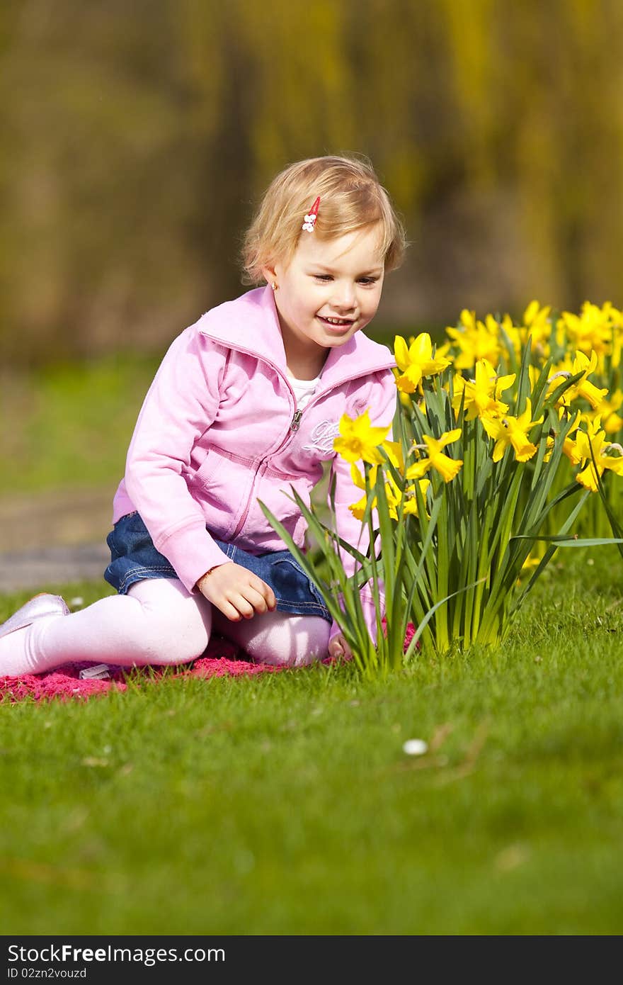 Little Girl And Daffodils In Park.