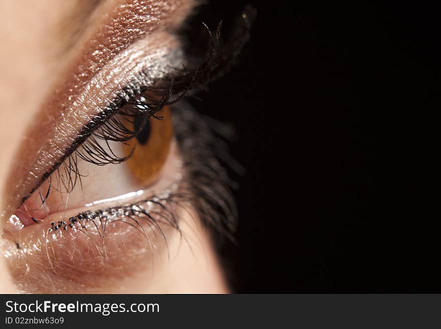 Close up of beautiful woman`s open brown eye peeping in darkness