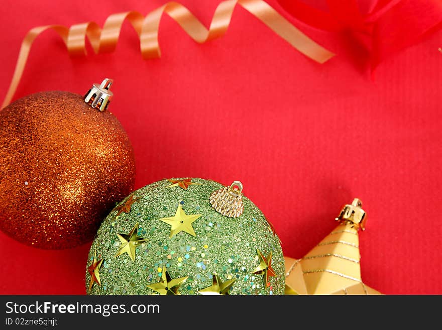 Gold Christmas star, colors ball and gold ribbon over red background