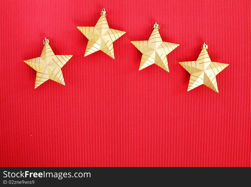 Four gold Christmas stars over red background