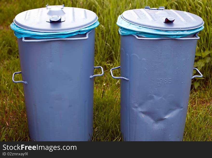 Two blue bins standing in a green meadow. Two blue bins standing in a green meadow