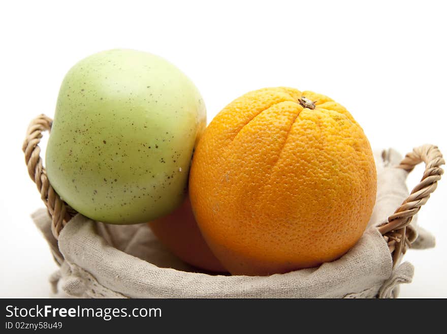 Oranges and apple in the basket with material coating