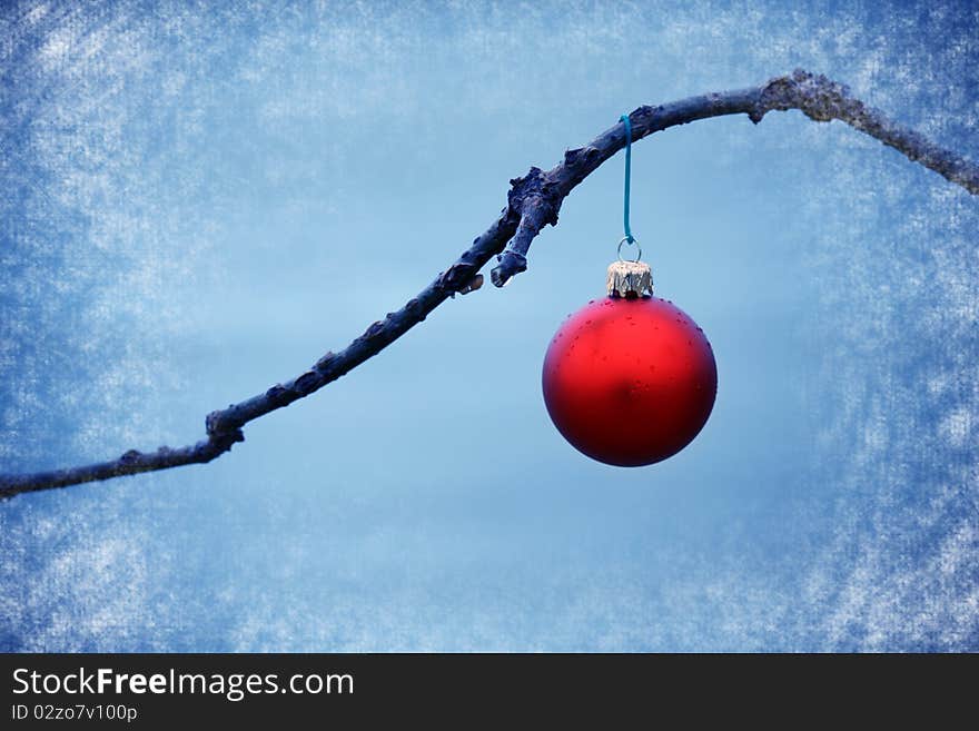 Red ball ornament on a branch in a blue background