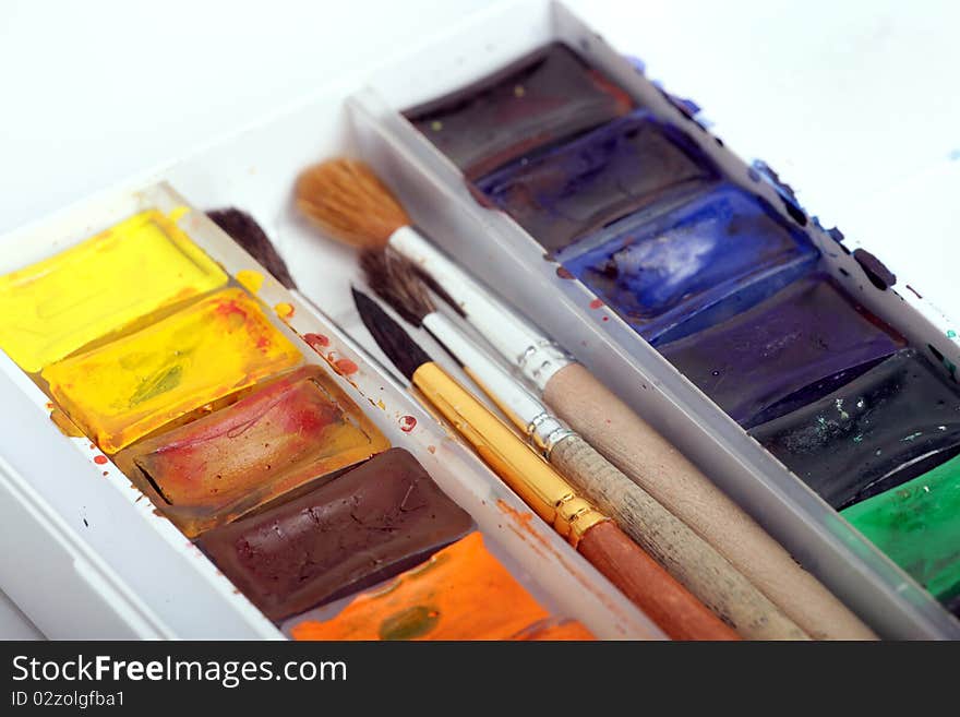 A pack of watercolour paints with brushes on a white background