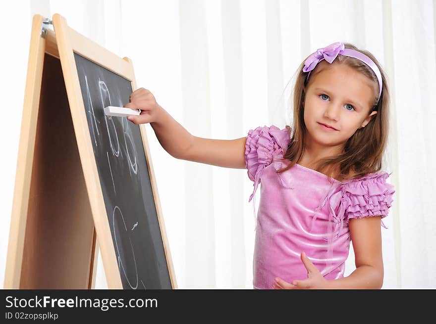 A little girl wrote in chalk on the graphite board. Receive their education.