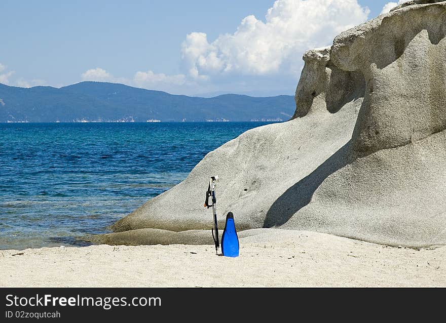 Sea rocks with a fishing gaff and swim fins at Kakoudia beach near the city of Ierissos in Chalkidiki North Greece. Sea rocks with a fishing gaff and swim fins at Kakoudia beach near the city of Ierissos in Chalkidiki North Greece